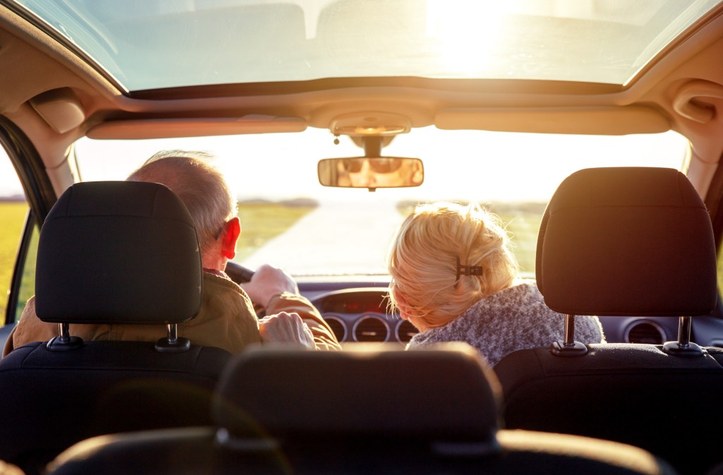 Rear view of smiling senior couple driving car.